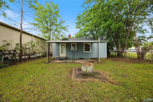 rear view of property featuring a fenced backyard, a chimney, and a yard
