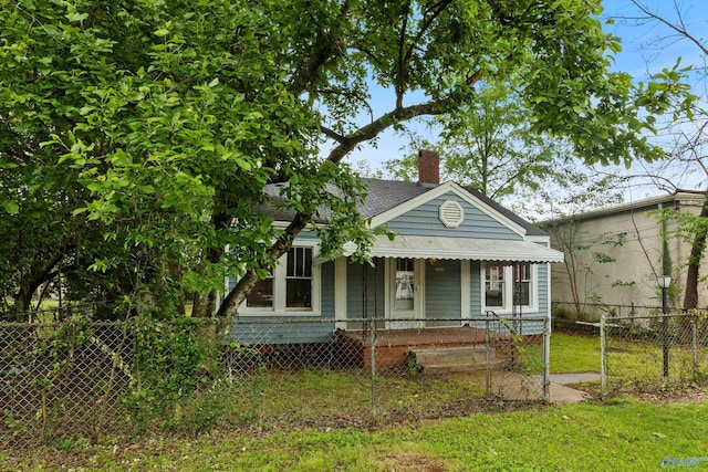 view of front of property featuring a fenced front yard, roof with shingles, a chimney, and a porch