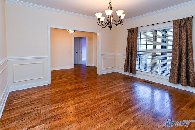 spare room with a notable chandelier, dark wood-type flooring, and ornamental molding