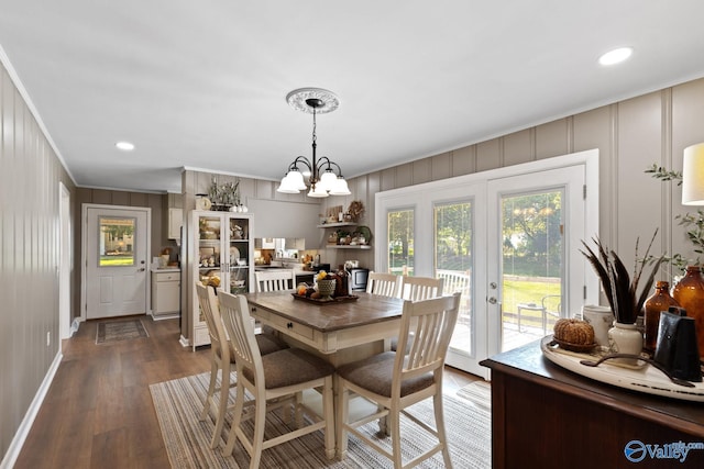 dining area with crown molding, an inviting chandelier, and dark wood-type flooring