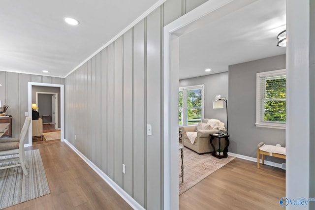 hall with light hardwood / wood-style flooring, a wealth of natural light, and crown molding