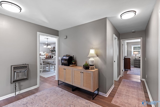 hallway featuring an inviting chandelier, heating unit, and hardwood / wood-style flooring