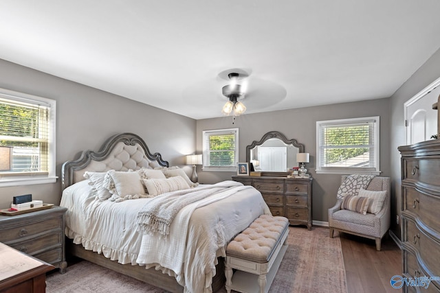 bedroom featuring ceiling fan, wood-type flooring, and multiple windows