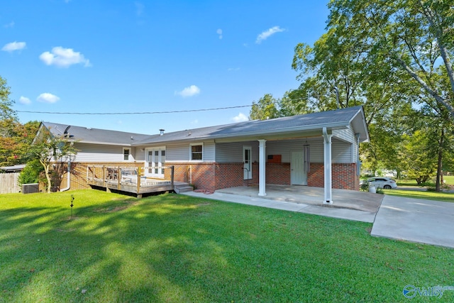 rear view of property with a lawn, a deck, and central AC