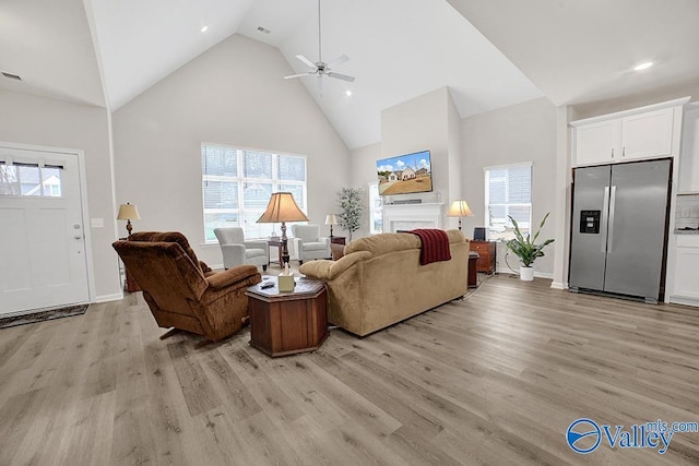 living room featuring ceiling fan, high vaulted ceiling, and light hardwood / wood-style floors