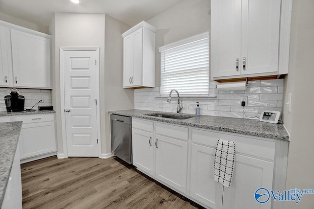 kitchen with sink, dishwasher, light stone countertops, light hardwood / wood-style floors, and white cabinets