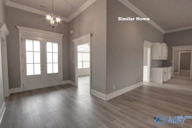 entrance foyer featuring an inviting chandelier, baseboards, ornamental molding, and wood finished floors