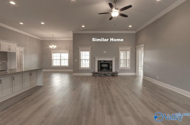 unfurnished living room with a sink, a fireplace, baseboards, and wood finished floors