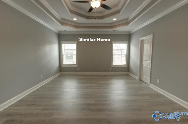 spare room featuring baseboards, a raised ceiling, ceiling fan, wood finished floors, and crown molding