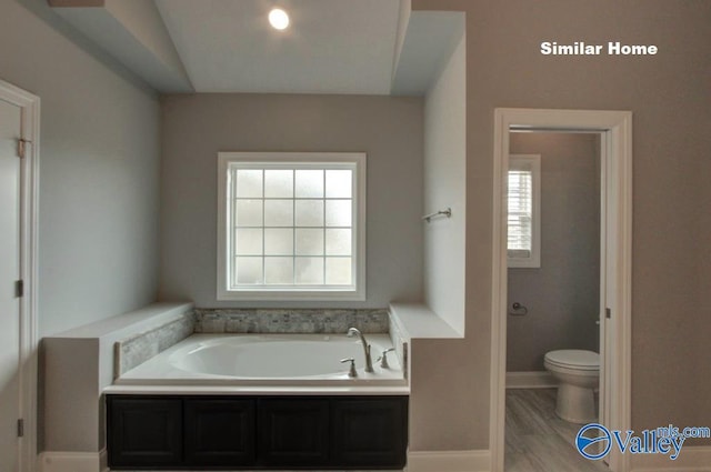 bathroom with toilet, baseboards, and a bath