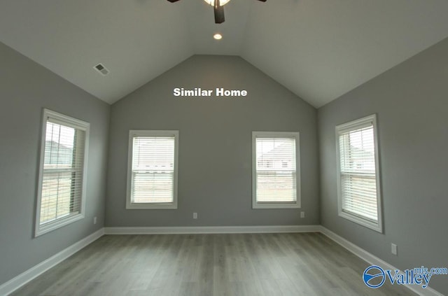 spare room featuring visible vents, baseboards, ceiling fan, light wood-style flooring, and vaulted ceiling