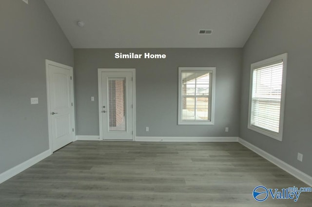 spare room featuring light wood-style floors, lofted ceiling, and baseboards