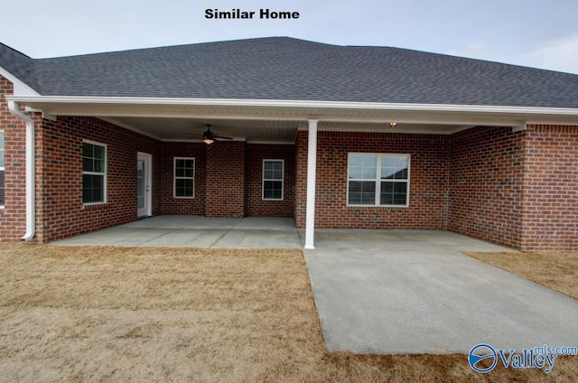 rear view of house featuring brick siding, a patio, roof with shingles, a lawn, and a ceiling fan