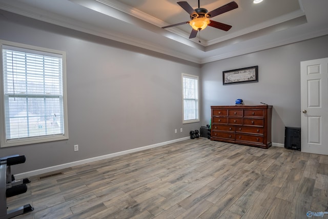 bedroom with wood-type flooring, ornamental molding, ceiling fan, and a tray ceiling