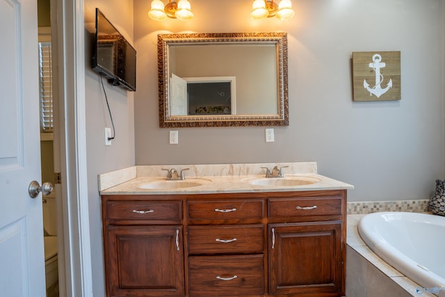 bathroom with a relaxing tiled tub, vanity, and toilet