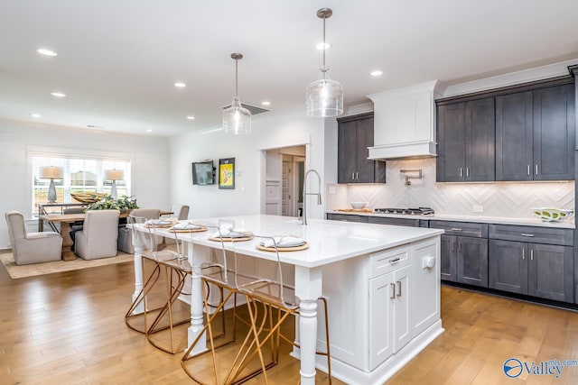 kitchen featuring light hardwood / wood-style flooring, tasteful backsplash, and an island with sink