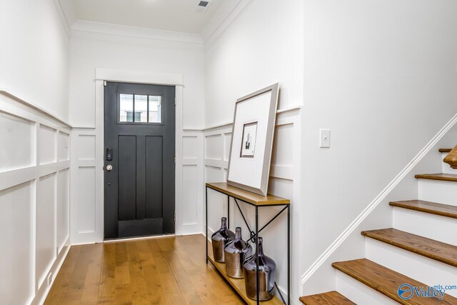 foyer entrance with ornamental molding and hardwood / wood-style flooring