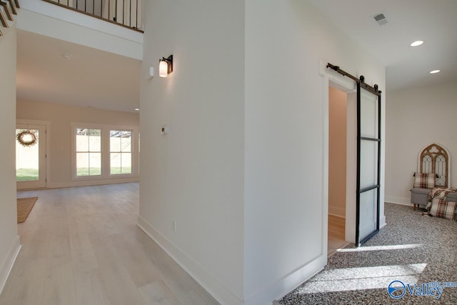 hall with light wood-type flooring and a barn door