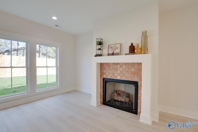 unfurnished living room featuring a tiled fireplace and light hardwood / wood-style floors