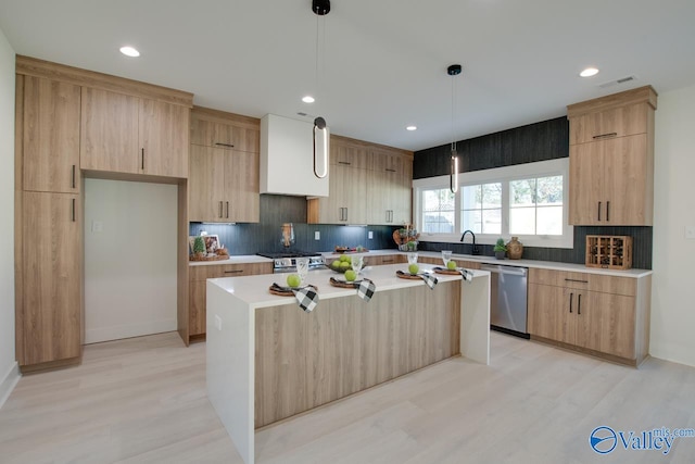 kitchen featuring light wood-type flooring, appliances with stainless steel finishes, a center island, and pendant lighting