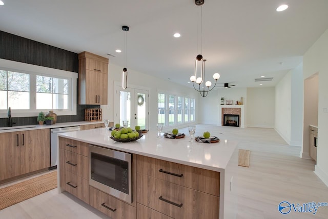 kitchen featuring pendant lighting, plenty of natural light, a kitchen island, and stainless steel appliances