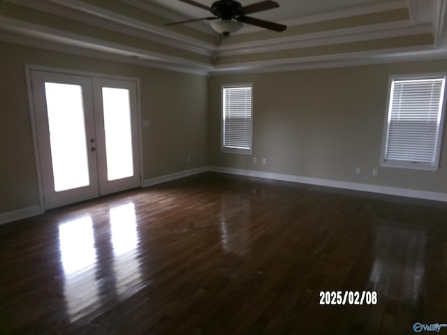 unfurnished room with dark hardwood / wood-style flooring, ornamental molding, ceiling fan, a tray ceiling, and french doors