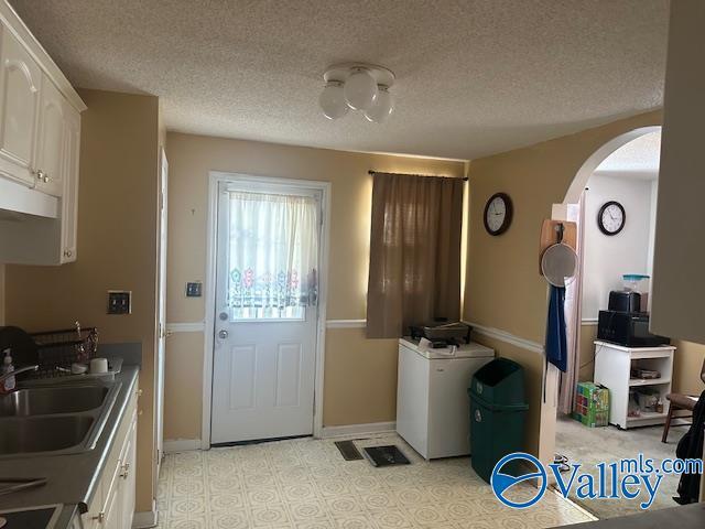 3613 Mcvay St, Huntsville, AL 35805 - kitchen featuring arched walkways, white cabinetry, and a textured ceiling