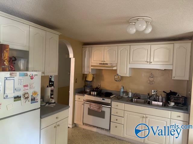3613 Mcvay St, Huntsville, AL 35805 - kitchen featuring white appliances, under cabinet range hood, arched walkways, dark countertops, and a textured ceiling