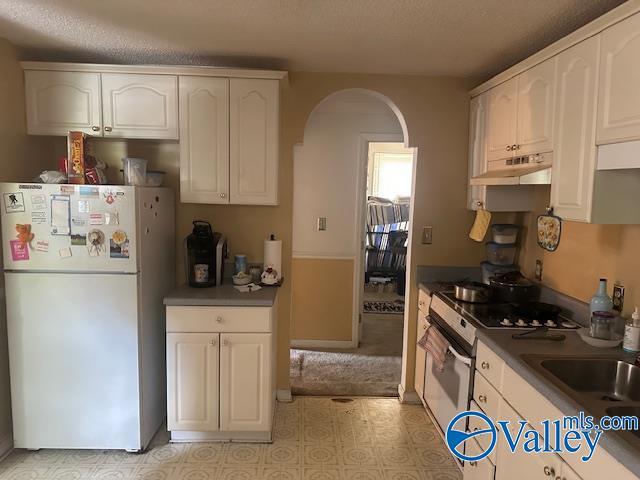 3613 Mcvay St, Huntsville, AL 35805 - kitchen with white appliances, under cabinet range hood, arched walkways, white cabinets, and light flooring