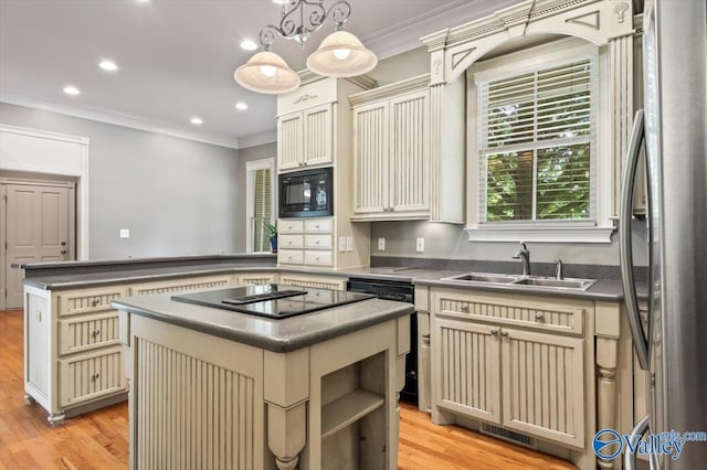 kitchen featuring dark countertops, cream cabinetry, and black appliances