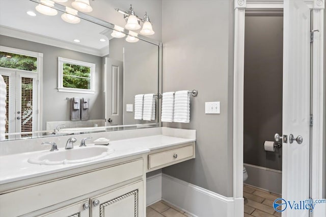 bathroom with toilet, ornamental molding, and vanity