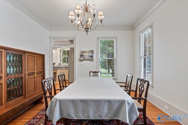 dining space featuring ornamental molding, a notable chandelier, and light wood-type flooring