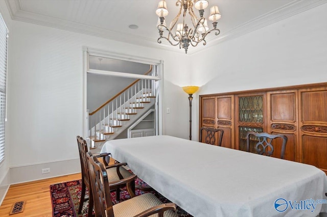 dining area featuring visible vents, wood finished floors, an inviting chandelier, and crown molding