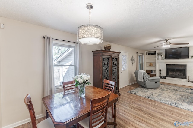 dining room with a fireplace, baseboards, a textured ceiling, and wood finished floors