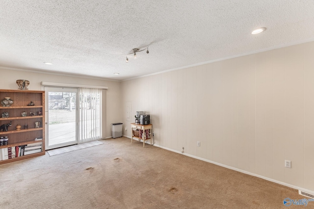 unfurnished room featuring a textured ceiling, carpet, and visible vents