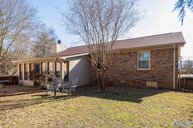 back of house featuring brick siding, a chimney, a lawn, crawl space, and fence