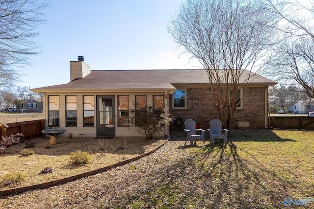 back of property with a sunroom, a chimney, fence, and brick siding