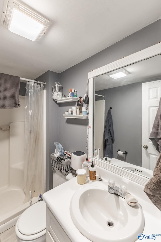 bathroom with toilet, a shower stall, and vanity