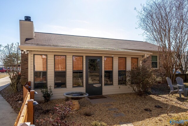 back of house with a chimney and brick siding