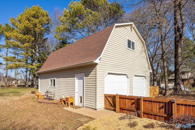 view of home's exterior featuring a garage, an outbuilding, roof with shingles, and a gambrel roof