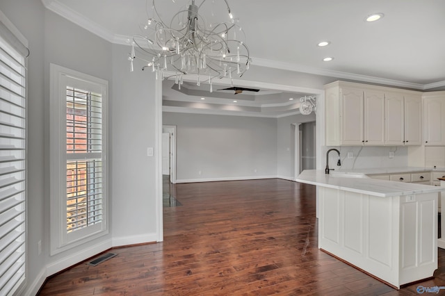 kitchen with kitchen peninsula, backsplash, ornamental molding, white cabinets, and sink