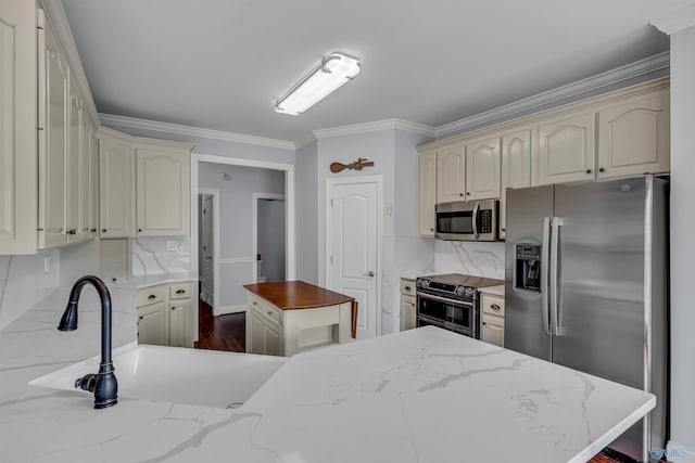 kitchen with backsplash, appliances with stainless steel finishes, and cream cabinets