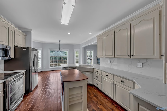 kitchen with decorative light fixtures, stainless steel appliances, decorative backsplash, sink, and ornamental molding