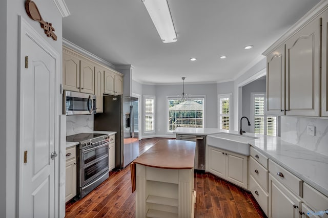 kitchen with kitchen peninsula, appliances with stainless steel finishes, backsplash, crown molding, and sink