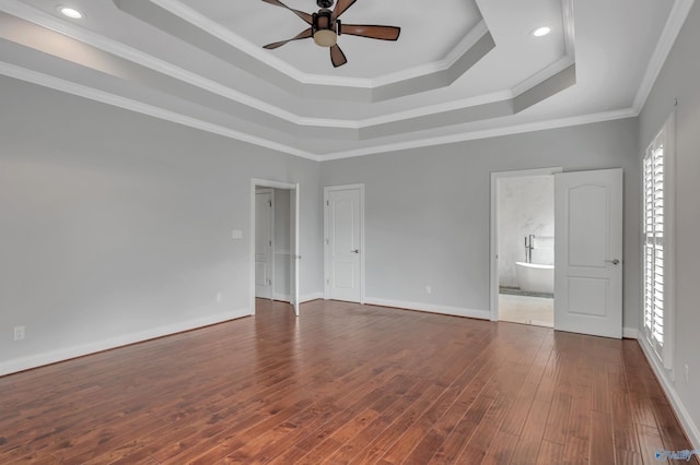 interior space featuring dark hardwood / wood-style flooring, a raised ceiling, ceiling fan, ensuite bathroom, and crown molding