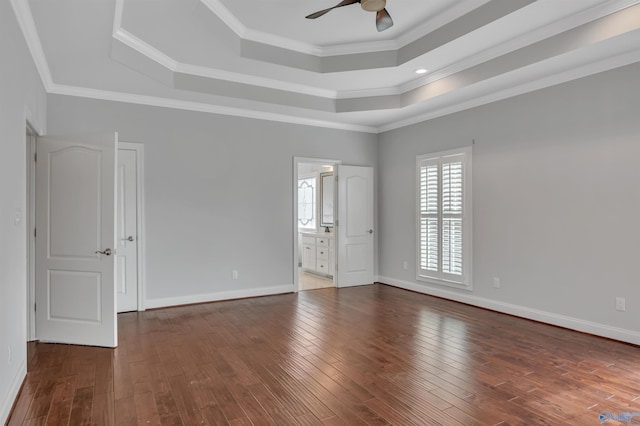 unfurnished room featuring ceiling fan, a tray ceiling, dark hardwood / wood-style flooring, and ornamental molding