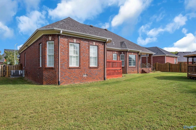 back of property with central AC unit and a yard