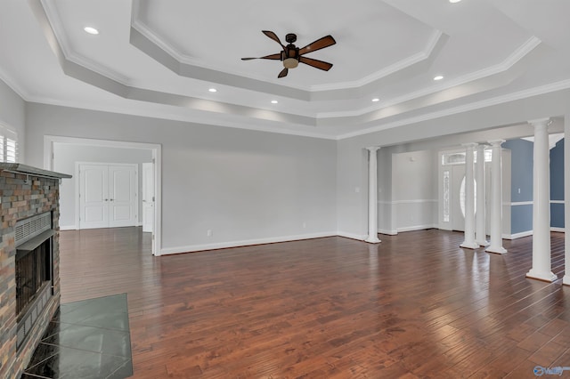 living room featuring ornate columns, ceiling fan, a tray ceiling, dark hardwood / wood-style flooring, and ornamental molding