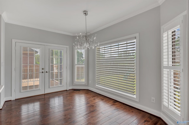 unfurnished dining area featuring dark wood-type flooring, crown molding, french doors, and a notable chandelier