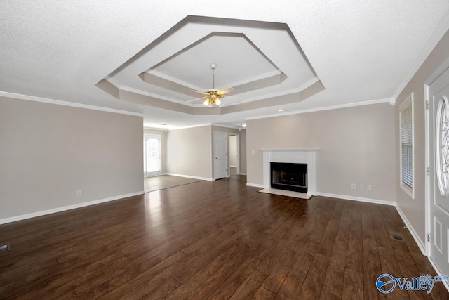 unfurnished living room with crown molding, a tray ceiling, dark hardwood / wood-style floors, and ceiling fan